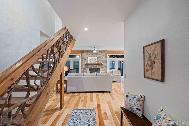 living room featuring a fireplace, french doors, light hardwood / wood-style floors, and ceiling fan