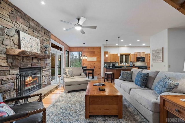 living room with ceiling fan, dark wood-type flooring, sink, a fireplace, and wood walls