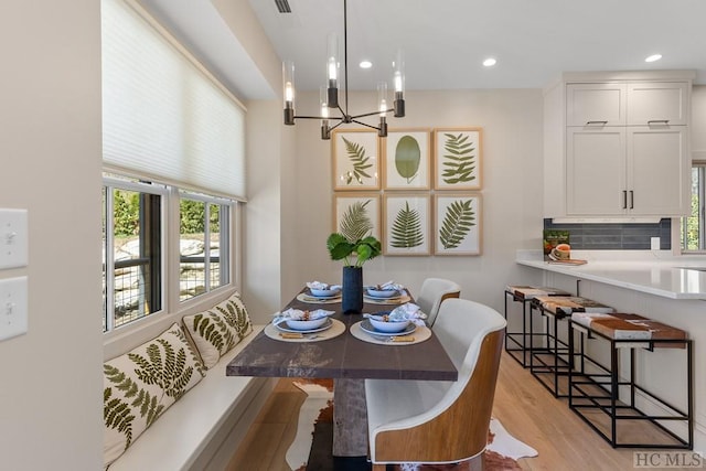 dining space with light wood-type flooring and a notable chandelier