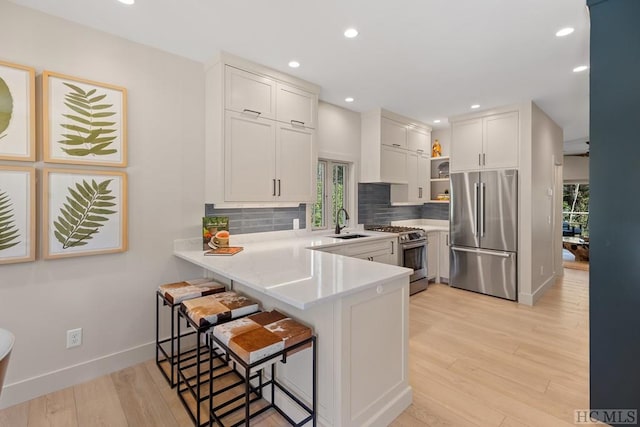 kitchen with a kitchen bar, appliances with stainless steel finishes, sink, kitchen peninsula, and white cabinets