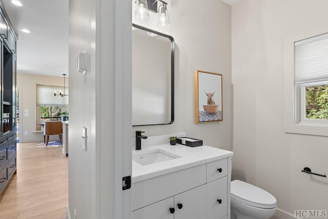 bathroom featuring toilet, vanity, hardwood / wood-style floors, and a healthy amount of sunlight