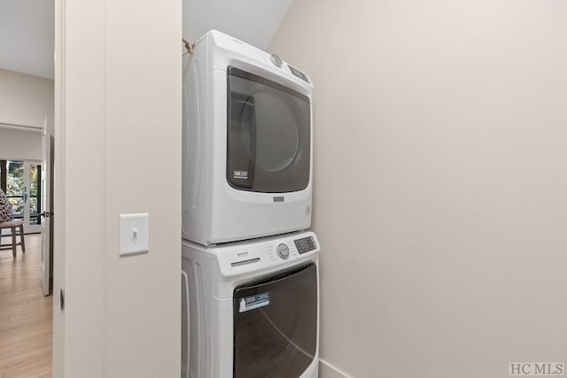 laundry area with light hardwood / wood-style flooring and stacked washing maching and dryer