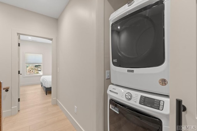 washroom featuring light wood-type flooring and stacked washer and clothes dryer