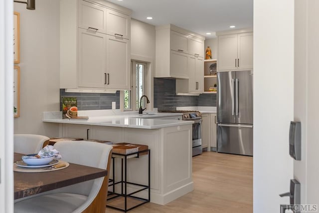 kitchen with appliances with stainless steel finishes, a kitchen breakfast bar, white cabinetry, and kitchen peninsula