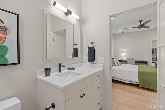 bathroom with hardwood / wood-style flooring, ceiling fan, vanity, and toilet