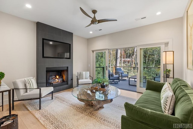 living room with a fireplace, ceiling fan, and light hardwood / wood-style floors