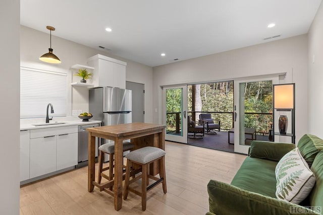 kitchen featuring sink, stainless steel appliances, pendant lighting, and white cabinets