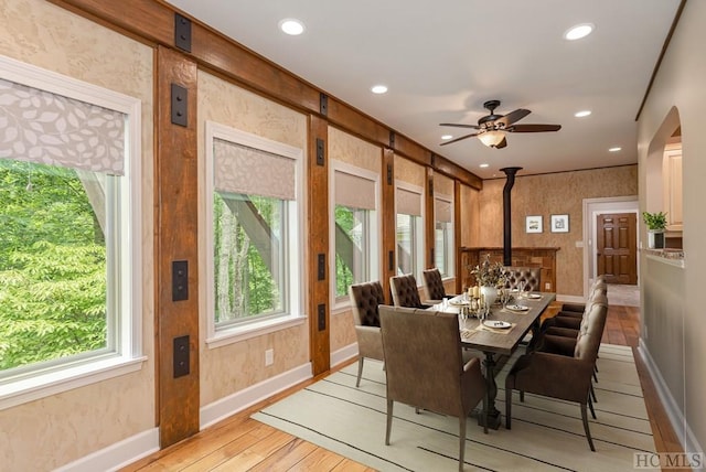 dining room featuring a wood stove, ceiling fan, and light hardwood / wood-style flooring