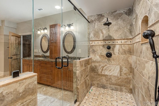 bathroom featuring a shower with door and vanity