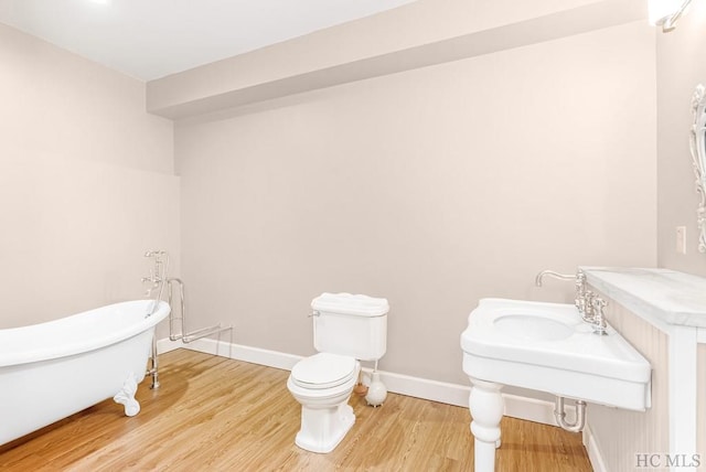 bathroom with hardwood / wood-style flooring, toilet, and a washtub