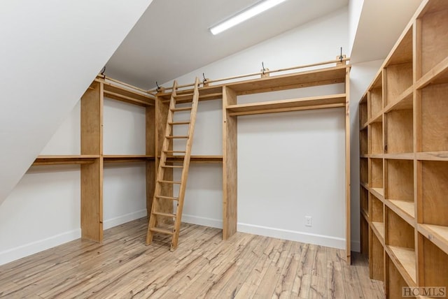 spacious closet featuring light hardwood / wood-style flooring and vaulted ceiling