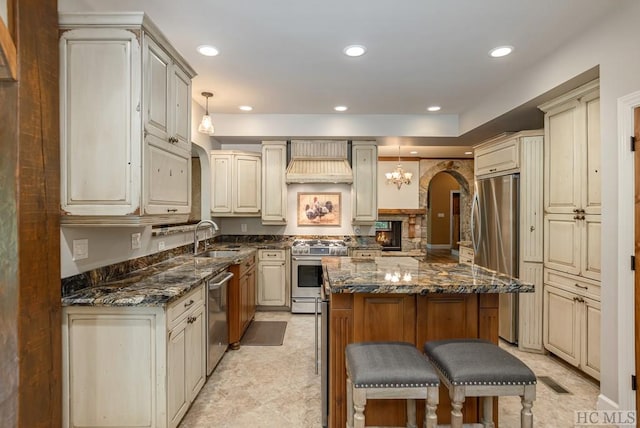 kitchen with stainless steel appliances, decorative light fixtures, sink, and dark stone countertops