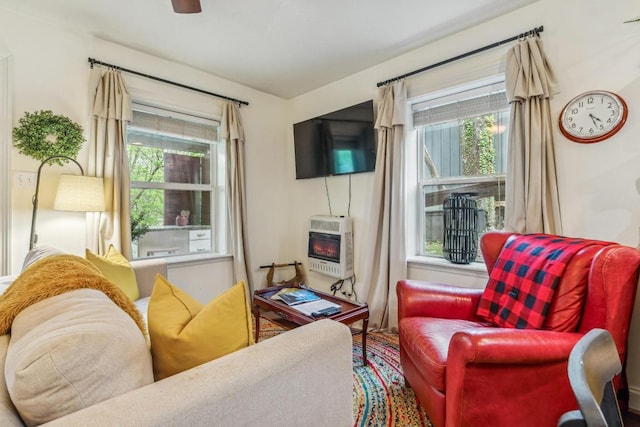 living area featuring heating unit and a ceiling fan