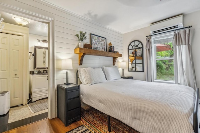 bedroom featuring a wall unit AC, wood finished floors, and wooden walls