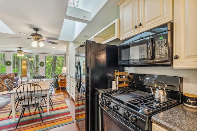 kitchen with black appliances, cream cabinets, ceiling fan, wood finished floors, and a skylight