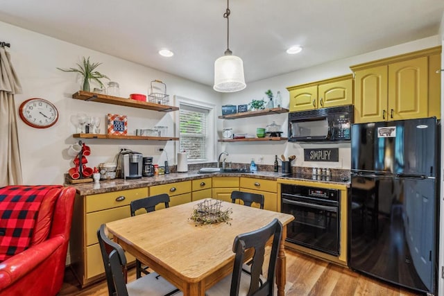 kitchen with black appliances, open shelves, a sink, light wood-type flooring, and dark countertops