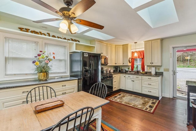 kitchen featuring a skylight, black appliances, dark countertops, dark wood-style floors, and pendant lighting