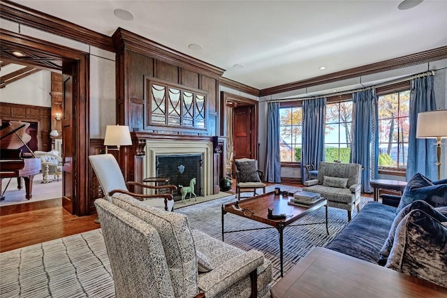 living area with crown molding, a decorative wall, a healthy amount of sunlight, and a fireplace
