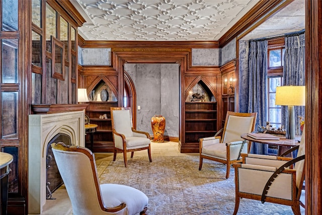 sitting room with crown molding, built in shelves, and a fireplace