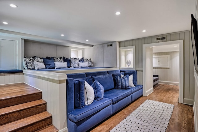 living room featuring a decorative wall, recessed lighting, wood finished floors, and visible vents