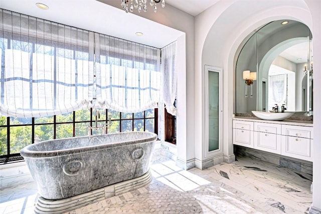 full bath with vanity, marble finish floor, a freestanding tub, baseboards, and recessed lighting