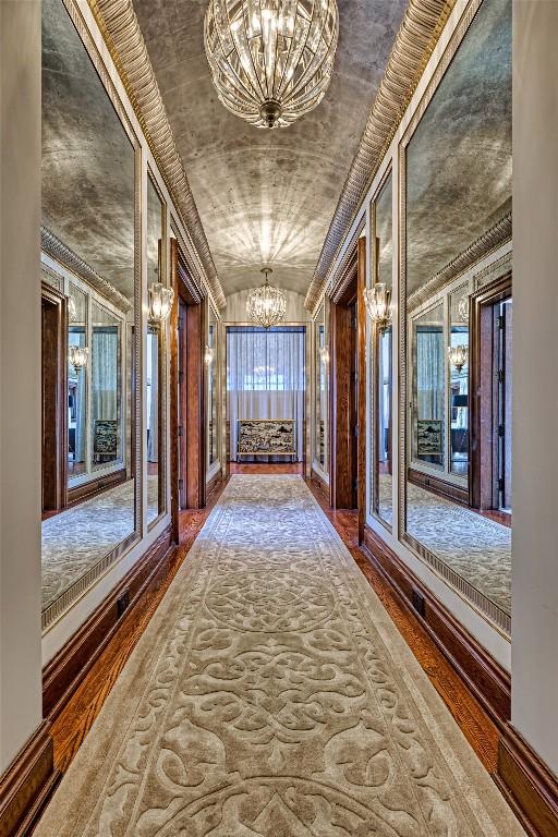 corridor with an inviting chandelier, hardwood / wood-style flooring, and lofted ceiling
