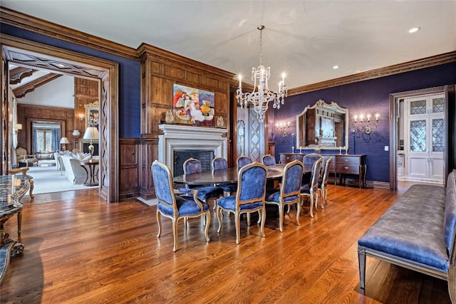 dining space featuring crown molding, a chandelier, wood finished floors, and a fireplace