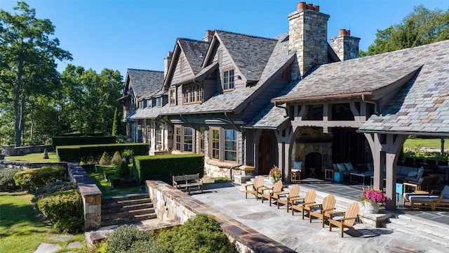 back of house featuring a patio, a high end roof, and a chimney