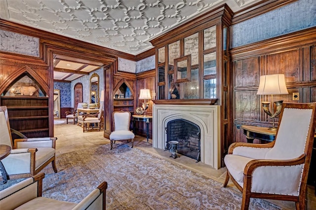 living area featuring wooden walls, ornamental molding, and a fireplace