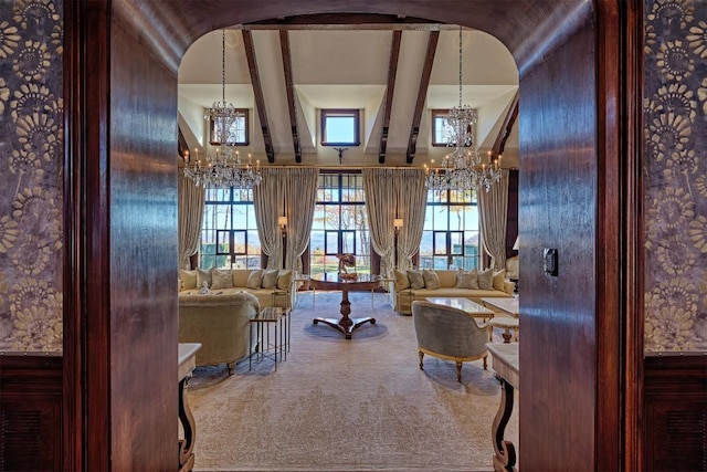living room featuring carpet, beam ceiling, a chandelier, and a wealth of natural light