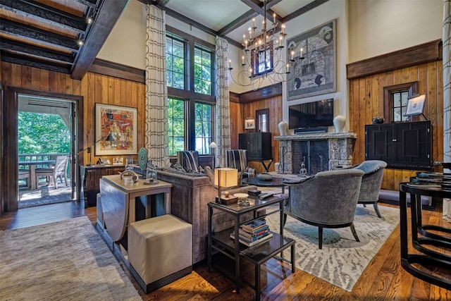 living area featuring wood walls, beam ceiling, and a towering ceiling