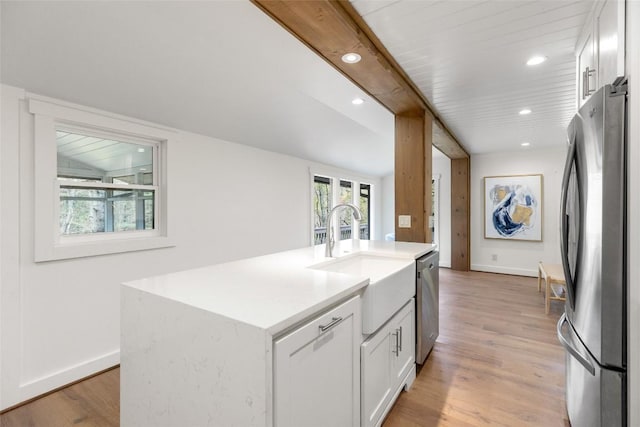 kitchen with baseboards, light wood-style flooring, appliances with stainless steel finishes, and a sink