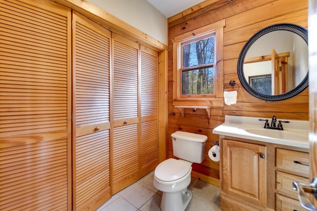 bathroom featuring toilet, wood walls, vanity, a closet, and tile patterned floors