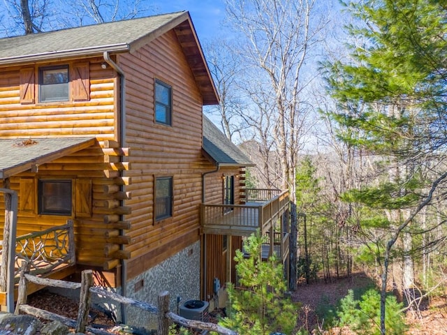 view of side of property with cooling unit, roof with shingles, a balcony, and log siding