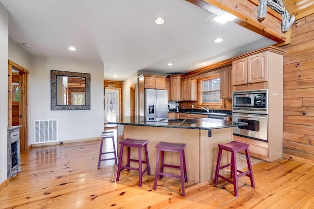 kitchen featuring appliances with stainless steel finishes, visible vents, a kitchen island, and a breakfast bar area