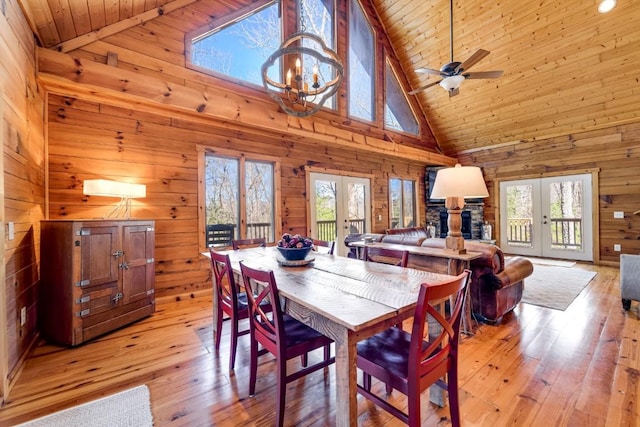 dining area with light wood finished floors, french doors, wood walls, and wooden ceiling