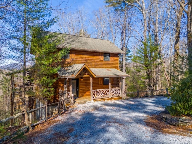 view of front facade featuring driveway, a porch, and fence