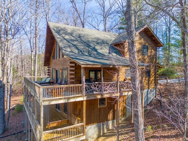 exterior space featuring log exterior and a shingled roof