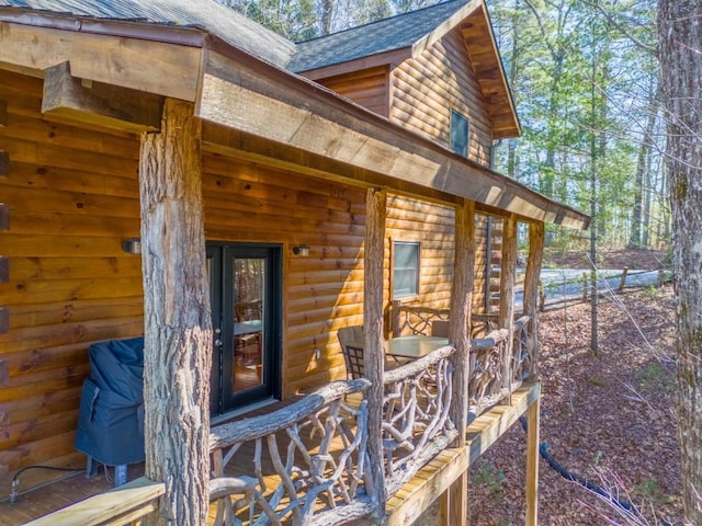 view of exterior entry featuring faux log siding and roof with shingles