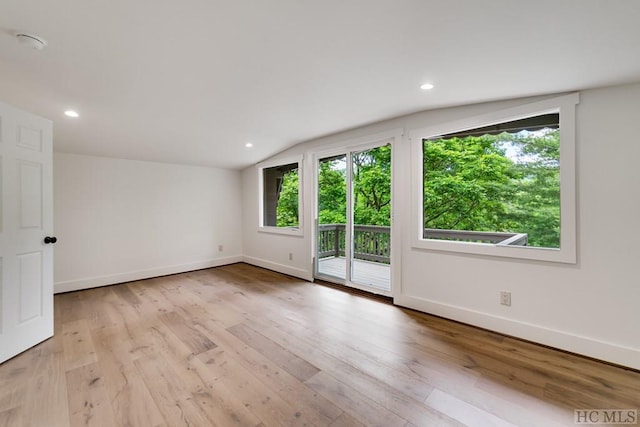 empty room with lofted ceiling and light hardwood / wood-style floors