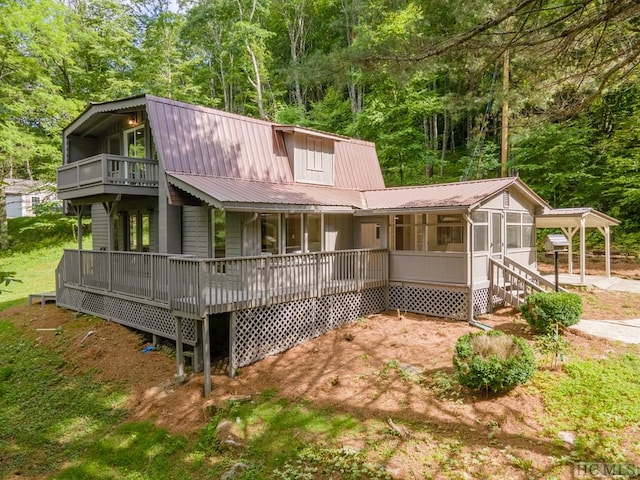 rear view of house featuring a wooden deck and a sunroom