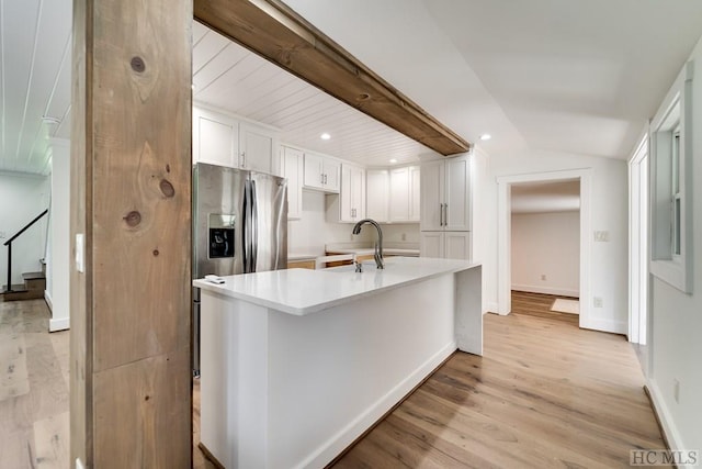 kitchen with vaulted ceiling, sink, white cabinets, light hardwood / wood-style floors, and stainless steel refrigerator with ice dispenser