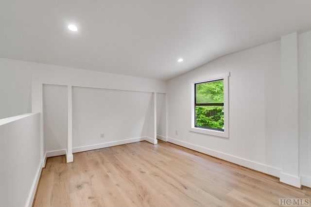 spare room featuring vaulted ceiling and light wood-type flooring