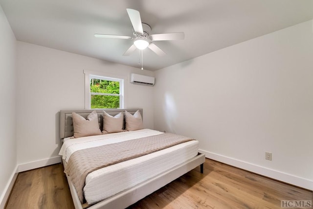 bedroom featuring ceiling fan, light hardwood / wood-style floors, and an AC wall unit