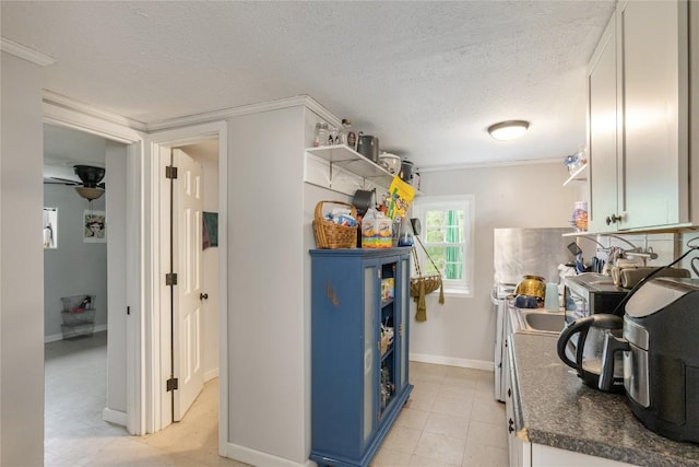 kitchen featuring dark countertops, open shelves, a textured ceiling, baseboards, and blue cabinets