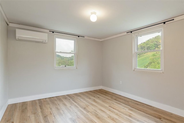 empty room with baseboards, a wall unit AC, and wood finished floors