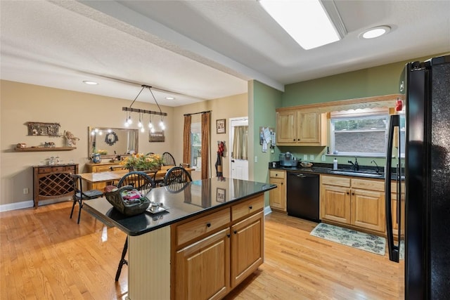 151 Rhododendron Ct, Sapphire, NC 28774 - kitchen with black appliances, dark countertops, light wood finished floors, a breakfast bar, and a kitchen island
