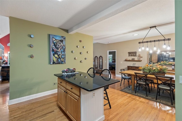 151 Rhododendron Ct, Sapphire, NC 28774 - kitchen with a kitchen breakfast bar, light wood-style floors, dark countertops, a kitchen island, and beamed ceiling