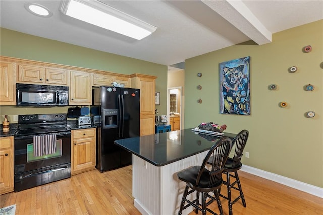 151 Rhododendron Ct, Sapphire, NC 28774 - kitchen featuring black appliances, light wood-style floors, a breakfast bar, dark countertops, and a center island