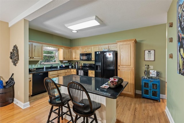 151 Rhododendron Ct, Sapphire, NC 28774 - kitchen with black appliances, light brown cabinetry, light wood-style floors, a kitchen breakfast bar, and recessed lighting